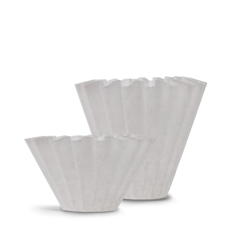 To hvide, riflede kaffefiltre vises på en almindelig baggrund, hvor det ene står lidt foran og kortere end det andet. Filtrene har et plisseret design og bruges til dryp kaffemaskiner.