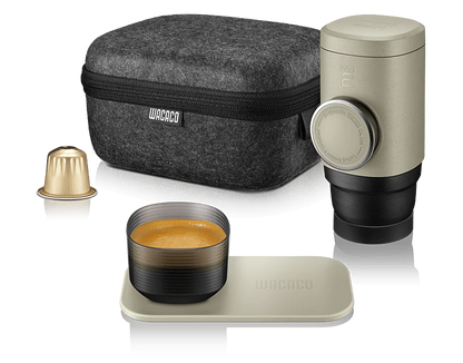 Oplev det ultimative bærbare espresso-kit med Wacacos slanke Minipresso NS2-etui i grå filt. Inkluderer en guldkapsel, cylindrisk espressomaskine med sideknop og et lille krus på en matchende underkop – et perfekt rejsesæt til kaffeentusiaster.