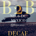 En person håndterer tørring af kaffebønner på en stor, flad overflade. Overlejret tekst lyder: "No. 06-dc - Mexico Decaf, Dark Roast (øko) (b), EverBean Business, koffeinfri kaffe.