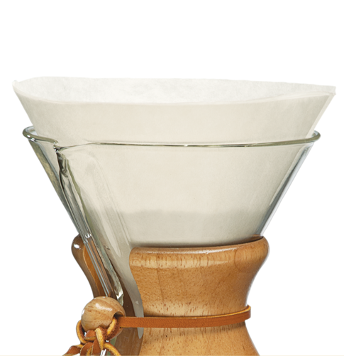 Nærbillede af en Chemex brygger fra Chemex med trækrave, læderbånd og hvide Kaffefiltre Papirfiltre i toppen. Baggrunden er almindelig hvid.
