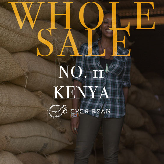 En smilende person står ved siden af store stakke af juteposer. Den ovenpåliggende tekst lyder: "ENGROS Nr. 11 · Kenya (w) fra EverBean - ideel til din Aeropress eller enhver anden måde, du nyder førsteklasses kaffebønner på.