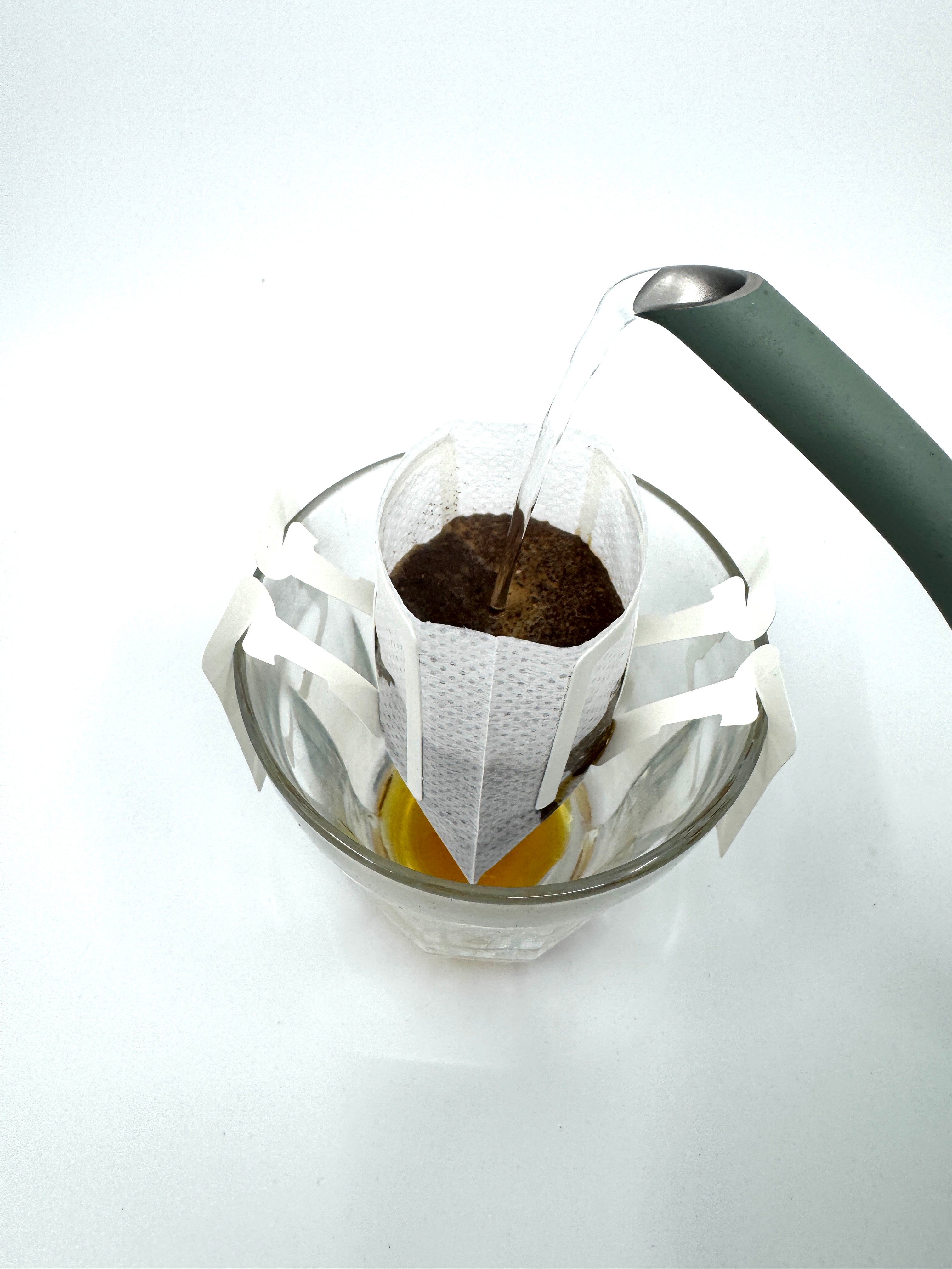 En kedel hælder varmt vand over EverBeans Single Serve, KeHo malet kaffe i et drypfilter over en glaskop for at demonstrere pour-over-metoden.