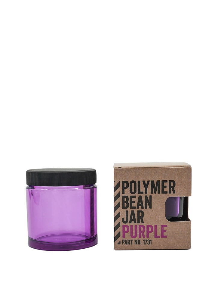 En gennemskinnelig lilla Comandante beholder med sort låg sidder ved siden af en brun papkasse mærket "Fødevaresikker Polymer Bean Jar med låg – Lilla" med fed sort og lilla skrift, del nr. 1731.