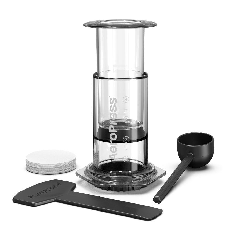 Aeropress AeroPress, Limited, Kaffebrygger: Inkluderer bryggekammer, stempel, sort måleske, rører og runde papirfiltre - alt stilrent arrangeret på hvid baggrund.