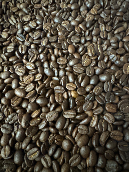 Et nærbillede af en stor bunke EverBeans No. 06 · Colombia Dark Roast bønner afslører deres blanke, mørkebrune udseende, hvilket fremhæver deres rige tekstur og varierende størrelse.
