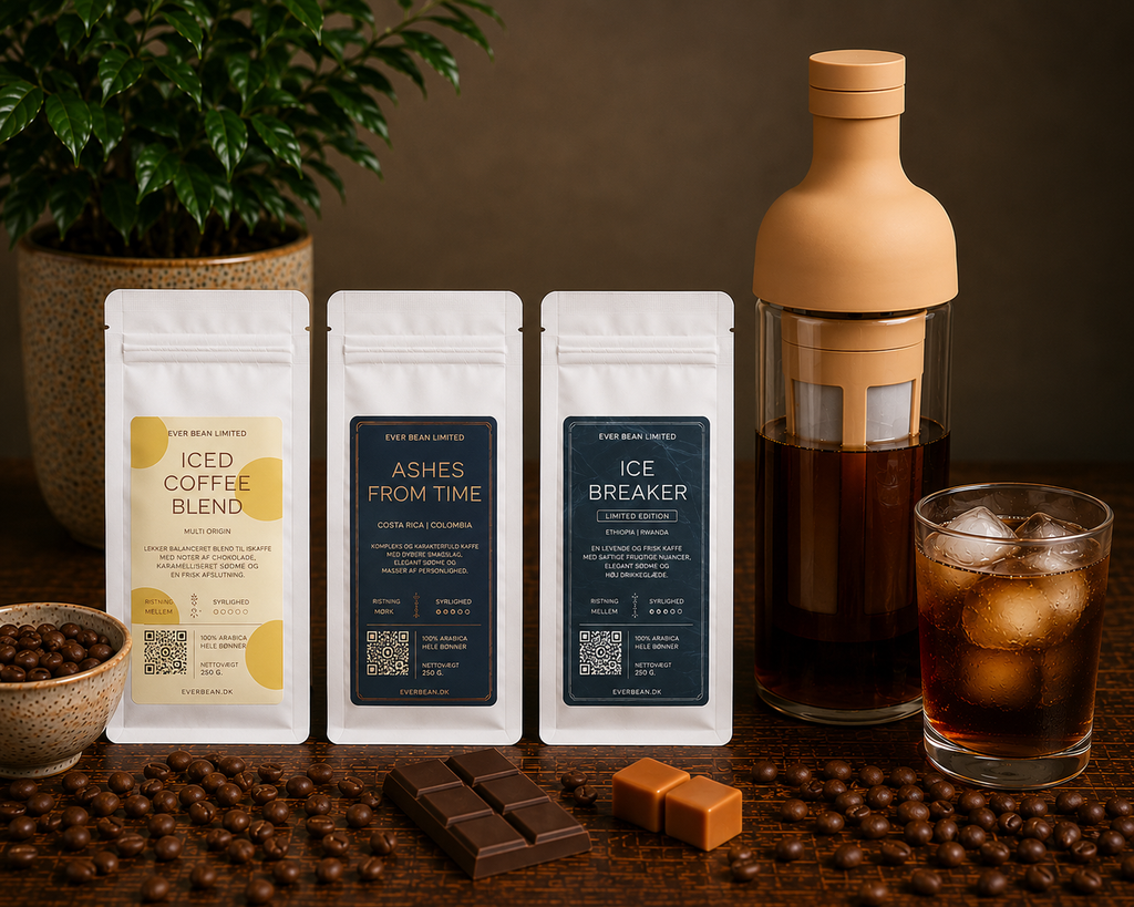 Tre kaffeposer fra EverBean ApS. står oprejst ved siden af en Hario Cold Brew-flaske, iskaffe, kaffebønner, chokolade og en grøn plante - perfekt til at nyde Cold Brew Smagspakke med brygger.