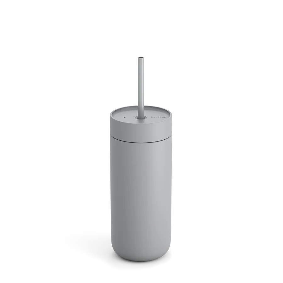 Fellow Carter Cold Tumbler, en slank grå cylinder med låg og sugerør, legemliggør minimalistisk elegance. Perfekt til iskaffe elskere, den blander stil og funktionalitet og kaster subtile skygger på en almindelig baggrund for den kræsne drikkevareentusiast.