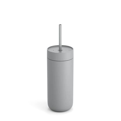 Fellow Carter Cold Tumbler, en slank grå cylinder med låg og sugerør, legemliggør minimalistisk elegance. Perfekt til iskaffe elskere, den blander stil og funktionalitet og kaster subtile skygger på en almindelig baggrund for den kræsne drikkevareentusiast.