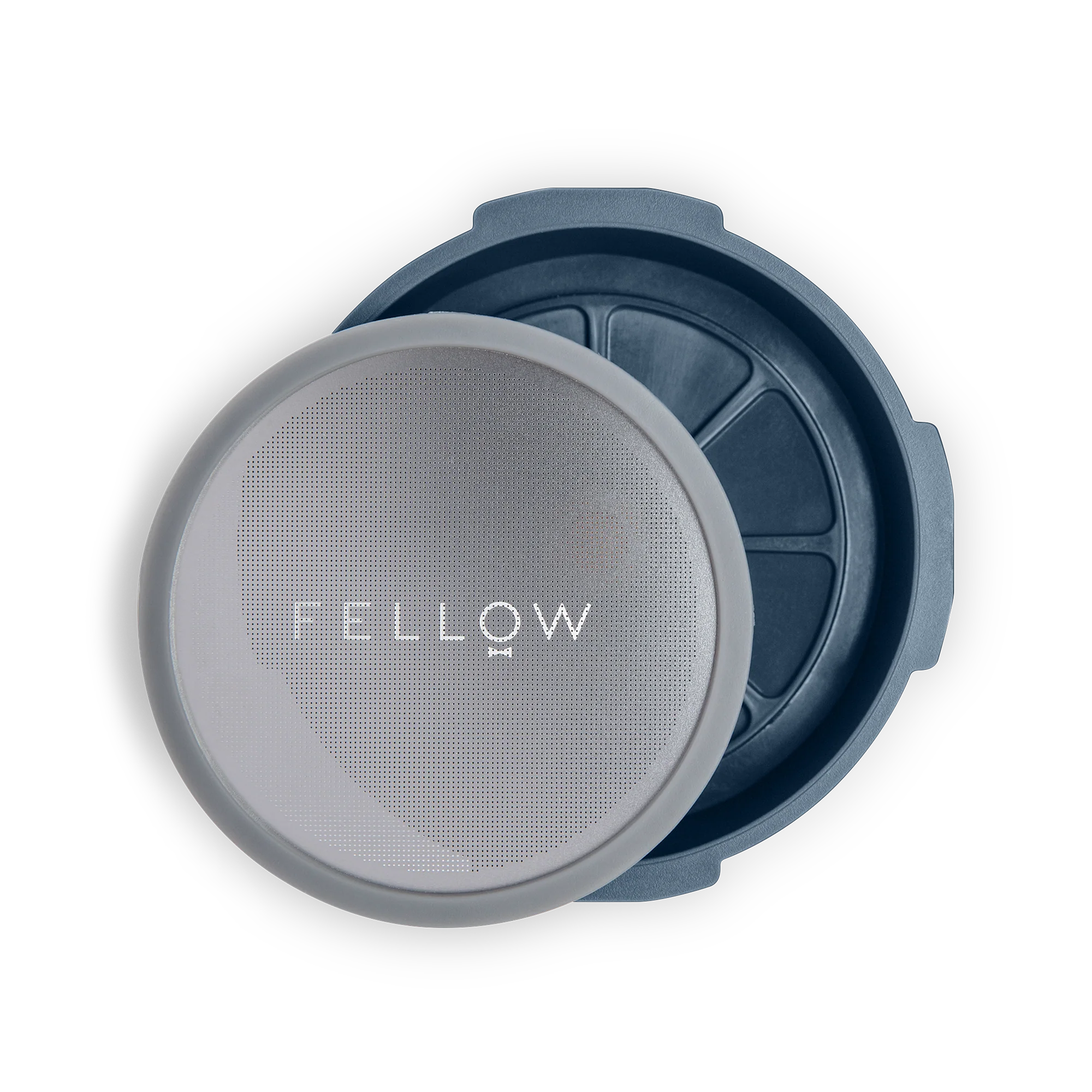 Fellow Prismo Attachment til AeroPress har et rundt, genanvendeligt kaffefilter med mærkenavnet "Fellow" på nettet. Den passer problemfrit sammen med en AeroPress, der hviler på en mørkeblå cirkulær holder, og tilbyder et slankt og moderne look på en gennemsigtig baggrund.
