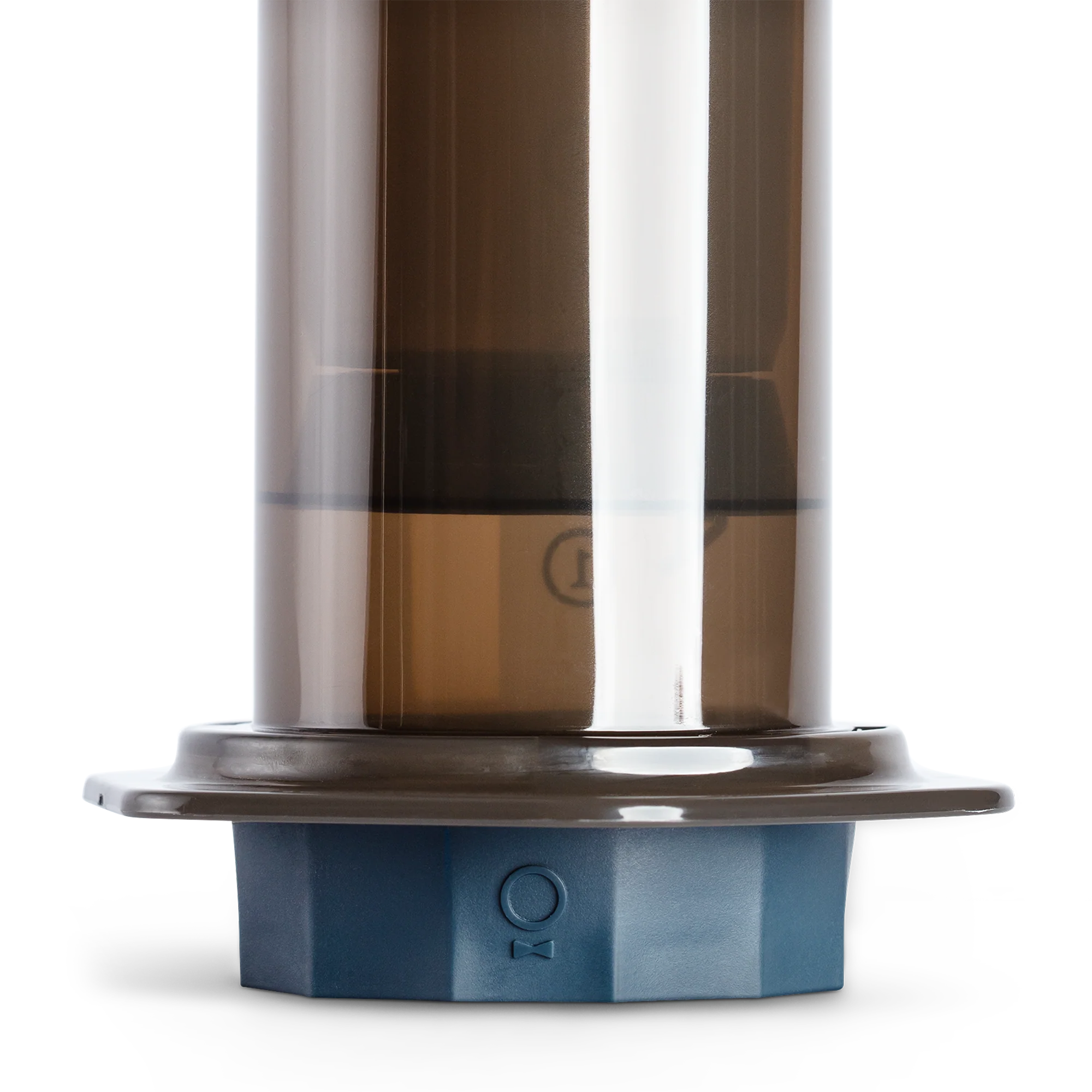 Fellow Prismo Attachment til AeroPress, en gennemskinnelig brun cylindrisk beholder med en grå base og måleskala, er designet til at forbinde sømløst med andre komponenter. Dens isolerede skærm fremhæver dens funktionalitet til espresso-stil kaffe.