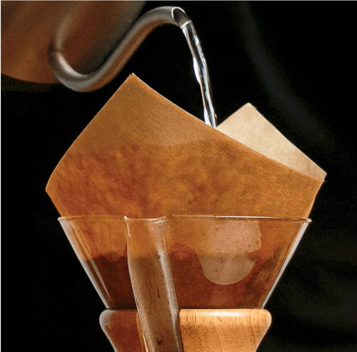 Varmt vand hældes over et papirfilter i en Chemex bryg pakke 2 fra EverBean ApS. og starter pour-over kaffebrygningsprocessen.