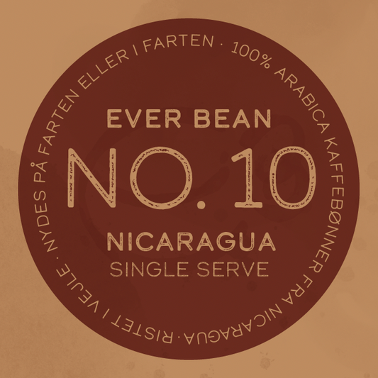 På en cirkulær kaffeetiket står der: "EverBean ApS. No. 10 Nicaragua, Single Serve." Rundt i kanten: "100% Arabica kaffebønner fra Sajonia Estate Coffee - nicaraguansk kaffe, nydes på farten eller i værtshjem.