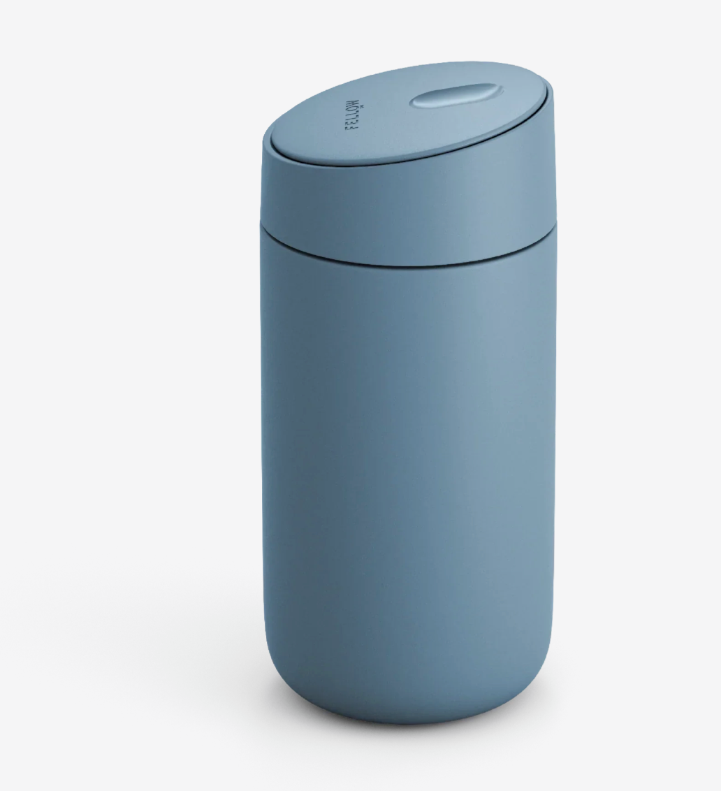 Et matblåt Fellow Carter Slide Mug (Termo Krus) med afrundet design og matchende låg, der har keramisk belægning for holdbarhed, vises på en almindelig hvid baggrund.