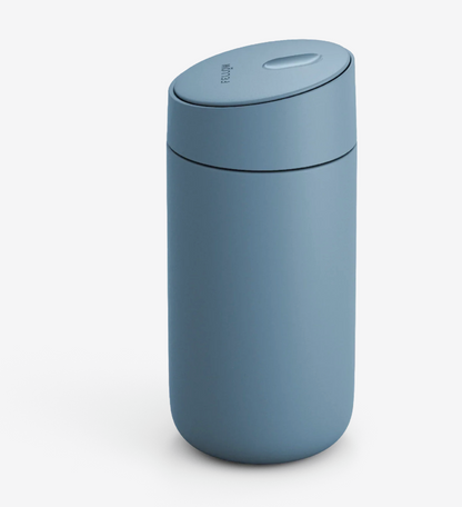 Et matblåt Fellow Carter Slide Mug (Termo Krus) med afrundet design og matchende låg, der har keramisk belægning for holdbarhed, vises på en almindelig hvid baggrund.