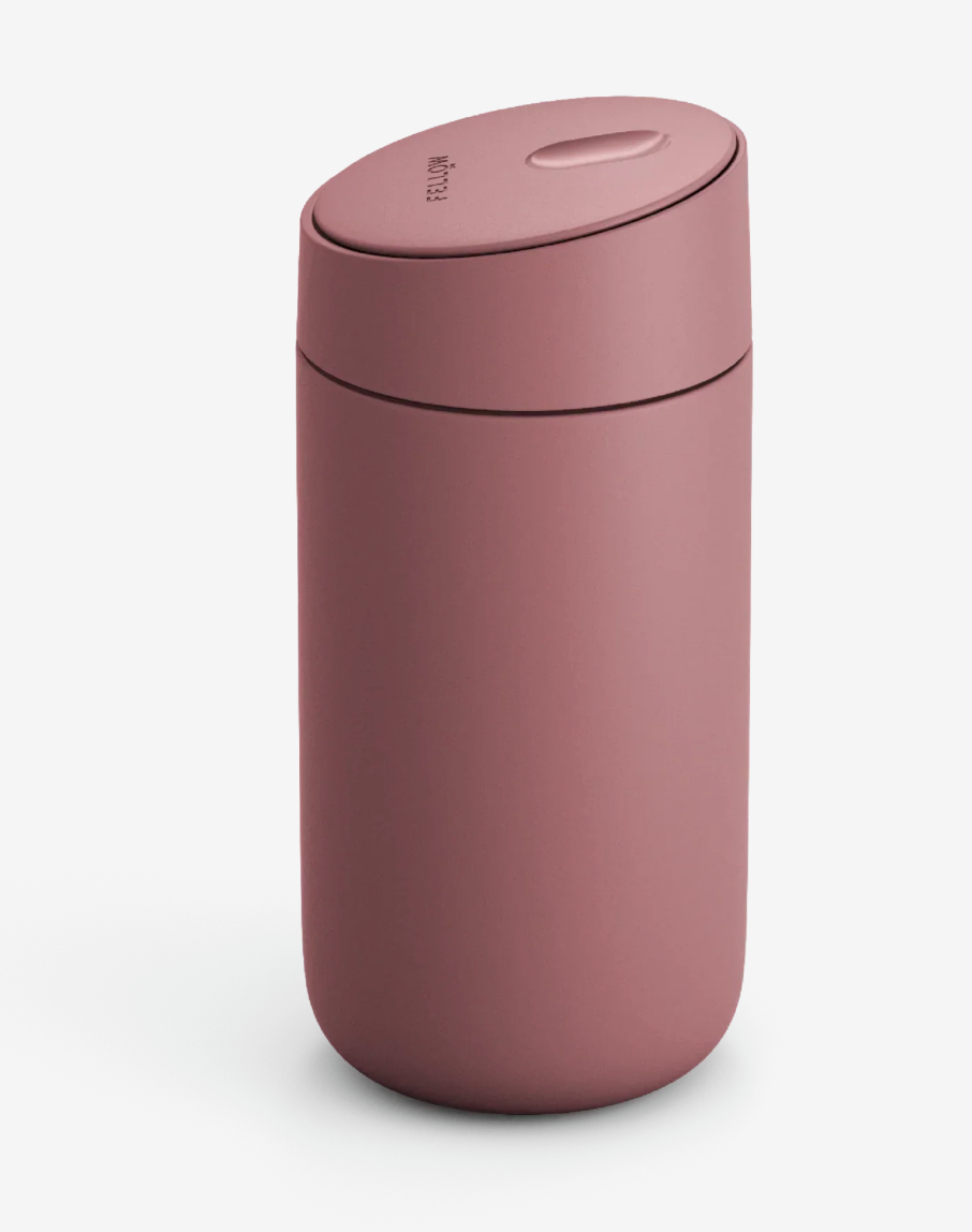 Fellow Carter Slide Mug (Termo Krus) har en mat rosa finish, en afrundet krop og et fladt, let skrånende låg, der står på en almindelig hvid baggrund.