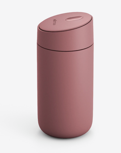 Fellow Carter Slide Mug (Termo Krus) har en mat rosa finish, en afrundet krop og et fladt, let skrånende låg, der står på en almindelig hvid baggrund.