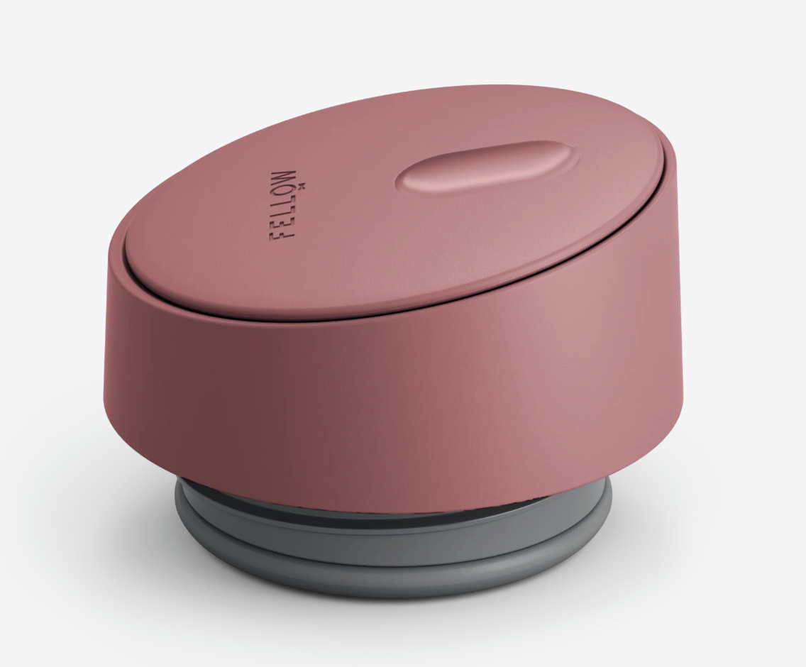 Et pink, ovalt Fellow-låg med en hævet knap, vist på en lys baggrund - ideelt til at parre med dit Fellow Carter Slide Mug termo krus.