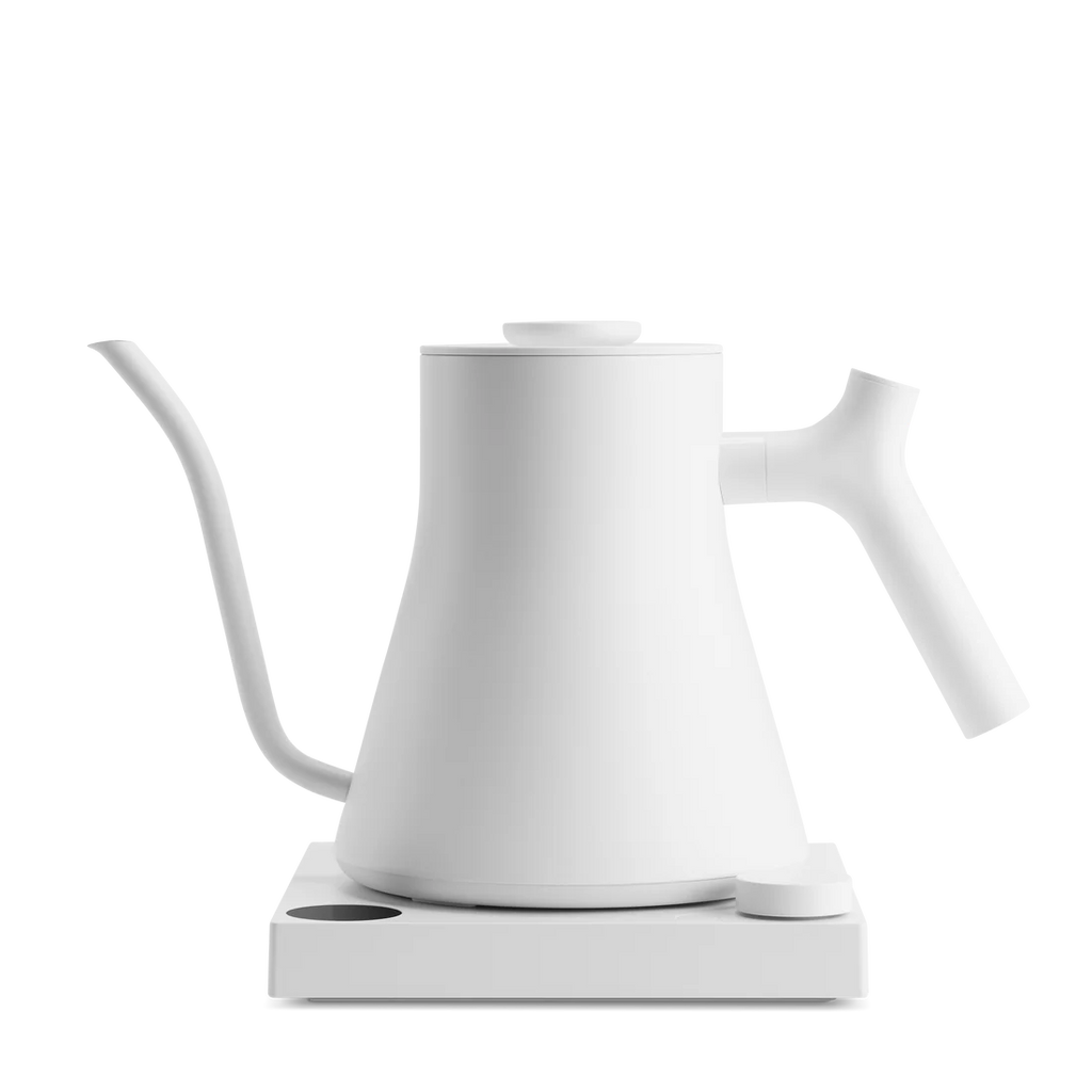 En minimalistisk Fellow Stagg EKG PRO 0,9 L elkedel i hvid med en lang svanehals-tud og håndtag står på en matchende hvid base mod en ensfarvet baggrund.