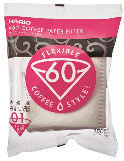 Hario Papir Filter Størrelse 01 emballagen har et pink og hvidt logo med "V60" og "Flexible Coffee Style" tekst. Det giver en dejlig kaffebrygningsoplevelse, indeholdende 100 filtre til 1-2 kopper, prydet med dekorativ grafik på klar plast.