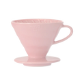 Hario Keramisk Drip Tragt i pink, der ligner en V60, inkluderer ribbede indvendige vægge for optimal kaffeekstraktion og en udspændt bund. Dens håndtag sikrer nem brug under manuelle brygningssessioner.