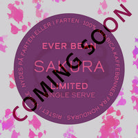 En cirkulær kaffeetiket med lyserøde blomstermønstre viser "EverBean Limited" og "Single Serve, Limited, Sakura". Inspireret af sakura-kaffe står der også "COMING SOON" diagonalt.