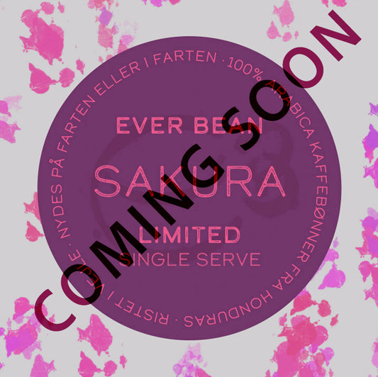 En cirkulær kaffeetiket med lyserøde blomstermønstre viser "EverBean Limited" og "Single Serve, Limited, Sakura". Inspireret af sakura-kaffe står der også "COMING SOON" diagonalt.