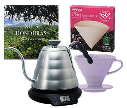 Billede af det vigtigste til kaffebrygning: en sølv-el-kedel med en buet tud, en æske med Hario V60-kaffepapirfiltre, en lavendel V60-drypper og EverBean's Startup · Filter, Medium. Perfekt til at øge produktiviteten under din morgenrutine eller som en del af din Startup Pakke.