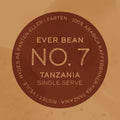 En rund kaffeetiket med "No. 07 - Tanzania, Single Serve" af EverBean ApS. i midten. På kanten står der: "100% vasket Arabica kaffebønner fra Tanzania kaffe. Ristet i Norge. Nydes på farten eller i farten.
