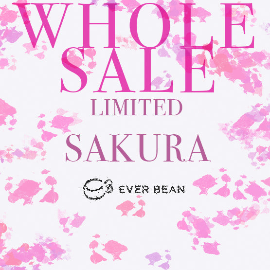 Den lyserøde tekst lyder "WHOLE SALE LIMITED SAKURA" på en hvid baggrund med lyserøde blomsteraccenter og henviser til Limited, Sakura (øko) (w), brygget på 100 % arabicabønner. Nedenfor ses EverBean Wholesale-logoet og brandnavnet i sort.